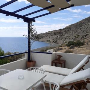a balcony with white chairs and a view of the ocean at Big Blue Studios Myrtos in Myrtos