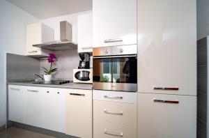 a kitchen with white cabinets and a microwave at Apartments Lazarić in Lopar +26 photos