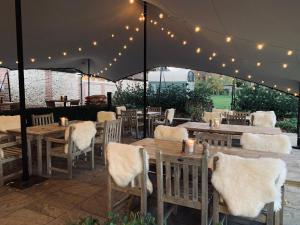 a restaurant with wooden tables and chairs under a tent at The Three Hills in Bartlow