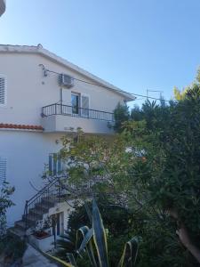 a white building with a staircase in front of it at Apartments Jerković Drašnice-1bd in Drašnice