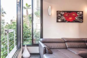 uma sala de estar com um sofá e uma grande janela em Luxury 3BR Apt Centrally Located & 5-min to Beach by Sea N' Rent em Tel Aviv