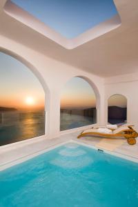 a swimming pool with a blue and white tub next to the ocean at Gold Suites - Small Luxury Hotels of the World in Imerovigli