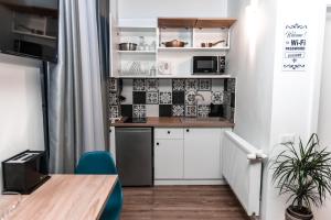 a small kitchen with white cabinets and a table at Puzzle Apartaments&Studios in Craiova