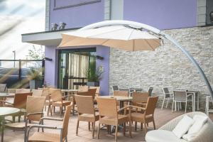 a patio with tables and chairs and an umbrella at Hotel Baya Strand in Milano Marittima