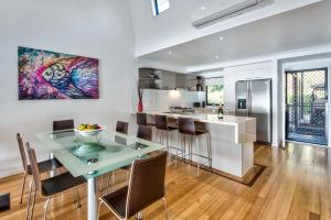 a kitchen and dining room with a glass table and chairs at Shorelines 2 on Hamilton Island by HamoRent in Hamilton Island