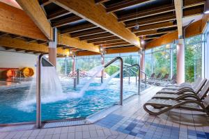 a large pool with a water slide in a building at Interferie Aquapark Sport Hotel Malachit in Świeradów-Zdrój