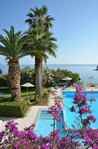 イストロにあるIstron Bay Hotelのヤシの木と紫の花が咲くリゾートスイミングプール