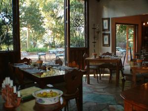 a dining room with tables and chairs and windows at Bohm's Zeederberg Country House in Hazyview