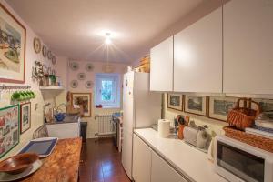 a kitchen with white cabinets and a wooden table at L'Atelier du Temps - PincherleStyle Apartment in Courmayeur