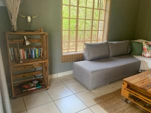 sala de estar con sofá y estante para libros en Impala Lily, en Marloth Park