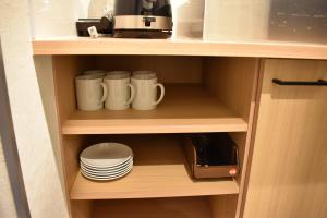 einem Schrank mit weißen Bechern und Platten in der Unterkunft Shinsaibashi House in Osaka