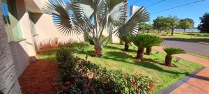 a yard with palm trees and flowers next to a building at Palmares Hotel in Guaíra