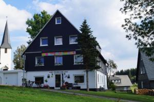 een zwart-wit huis met een kerk bij Hotel Pension De Gasterei in Winterberg