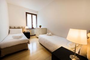 a bedroom with two beds and a lamp and a window at Appartamenti Meridiana in Torri del Benaco +27 photos