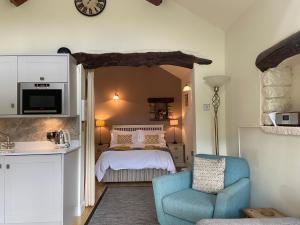 a bedroom with a bed and a chair and a kitchen at Swallow Barn in Chelmorton