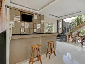 a kitchen with a bar with two stools at Super OYO 3904 Kiki Residence Bali in Seminyak