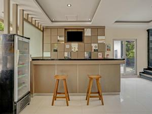 a kitchen with two stools and a counter with a refrigerator at Super OYO 3904 Kiki Residence Bali in Seminyak