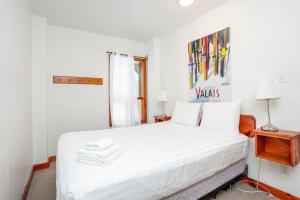 een witte slaapkamer met een groot bed met witte lakens bij Blue Mtn Chalet with Hot Tub and Sauna, Sleeps 20 in Blue Mountains
