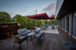 un patio con sedie, tavoli e ombrellone rosso di Best Western Aries Hotel a Vicenza