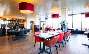 a dining room with tables and red chairs at Bastion Hotel Schiphol Hoofddorp in Hoofddorp