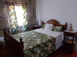 1 dormitorio con 1 cama con colcha de flores en A casa do pátio en Montalegre