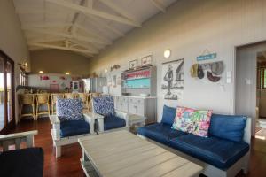 uma sala de estar com sofás azuis e uma cozinha em Mar Azul 6, Ponta do Ouro road, Ponta Malongane em Ponta Malangane