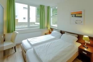 a bedroom with a bed and a chair and windows at Dormio Resort Eifeler Tor in Heimbach +38 photos