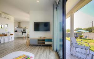 VILLAS D'ELBA في جيزنوكسيا: غرفة معيشة مع طاولة وتلفزيون على الحائط