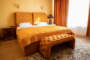 1 dormitorio con cama grande de color naranja y banco en Seven Eleven Apartment HOTEL in Most City, en Dnipro