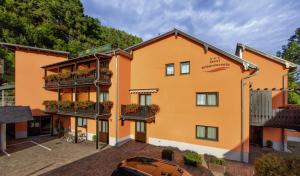 een oranje gebouw met balkons en een parkeerplaats bij Hotel Elbpromenade in Bad Schandau