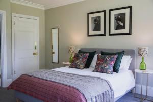 ロス・オン・ワイにあるBridstow Guest Houseのベッドルーム1室(ベッド1台、テーブル2台、壁に2枚の写真付)