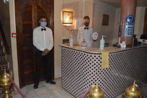 two men wearing masks standing next to a counter at Riad Golf Stinia in Meknès