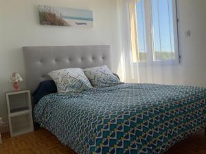 - une chambre avec un lit doté d'une couette bleue et d'une fenêtre dans l'établissement Maison de vacances familiale Kairon Plage B, à Saint-Pair-sur-Mer