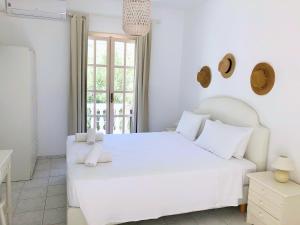 a white bedroom with a white bed and a window at Petrino in Ambrami