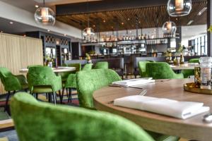 een restaurant met houten tafels en groene stoelen bij Farm house Van der Valk Hotel Leeuwarden in Leeuwarden