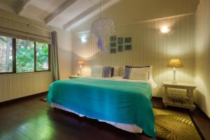 a bedroom with a large bed with a green blanket at Mar Azul 5 in Ponta Malongane