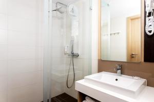 
a bathroom with a shower, sink, and mirror at Portobello Wellness & Yacht Hotel Esztergom in Esztergom
