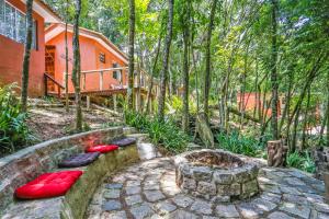 um jardim com almofadas vermelhas e uma casa na floresta em Chácara Flor de Iris em Piraquara