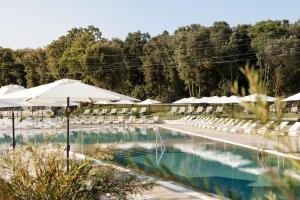 a swimming pool with white umbrellas and chairs at Apartment Castel in Bale