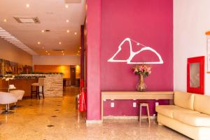 a lobby with a pink wall with a vase of flowers at Pompeu Rio Hotel in Rio de Janeiro