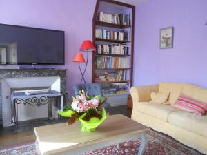 uma sala de estar com um sofá e uma televisão em AMBIANCES chambres d 'hôtes em Baye