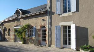 un edificio con puertas azules y blancas en una calle en Le Petit Bois en Château-la-Vallière