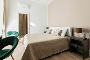 um quarto branco com uma cama e uma cadeira verde em FJ Bianco Guest House em Nápoles