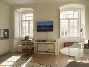 uma sala de estar com uma mesa e duas janelas em Chiado bright modern apt with ac elevator em Lisboa