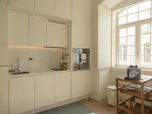 uma cozinha com armários brancos e uma janela em Chiado bright modern apt with ac elevator em Lisboa