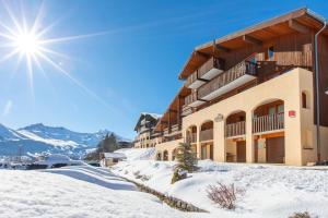 a building in the snow with the sun in the sky at Vacancéole - Résidence La Duit in La Léchère