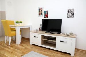 un soggiorno con TV e tavolo con sedia gialla di Apartman Frida a Nikšić