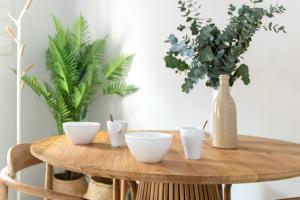einem Holztisch mit vier weißen Schalen darauf mit einer Vase in der Unterkunft Tinto Townhouse by Olala Homes in Sevilla