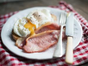 a plate of food with eggs and meat on a table at The Croft where Architecture Meets Serenity in Lochearnhead