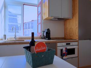 a bottle of wine in a basket on a kitchen counter at Mouraria lovers cozy bright apartment in Lisbon